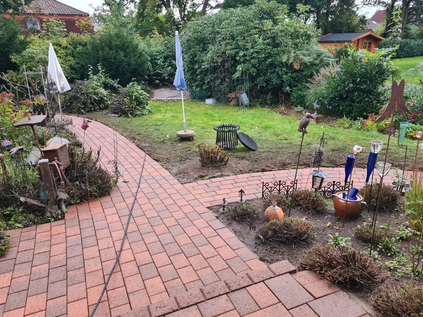 Geschwungener Gartenweg mit sauber verlegten roten Pflasterklinkern