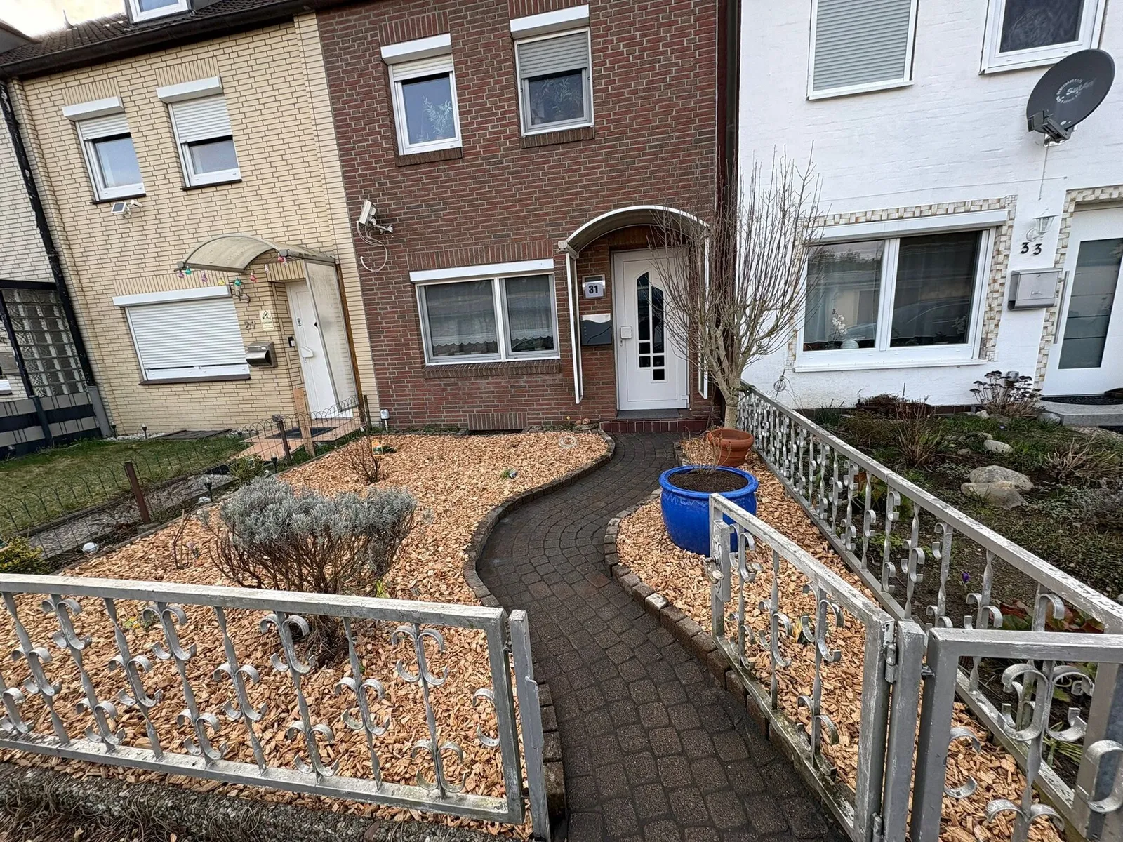Neugestalteter Vorgarten mit geschwungenem Pflasterweg und Rindenmulchbeet